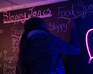 sloppy jones props master Yasmin on set writing on blackboard